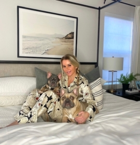 blonde girl sitting on bed with two french bulldogs