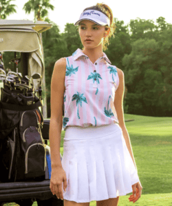 Blonde woman in pink golf shirt and white golf skirt on the golf course next to golf cart