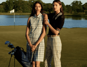 Two brunette women on golf course with plaid dress and plaid pants