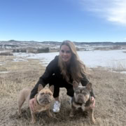 blonde woman with two french bulldogs wearing GPS dog tracker collars