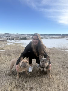 blonde woman with two french bulldogs wearing GPS dog tracker collars