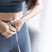 woman in yoga pants measuring her waist