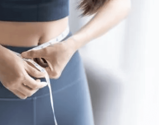 woman in yoga pants measuring her waist